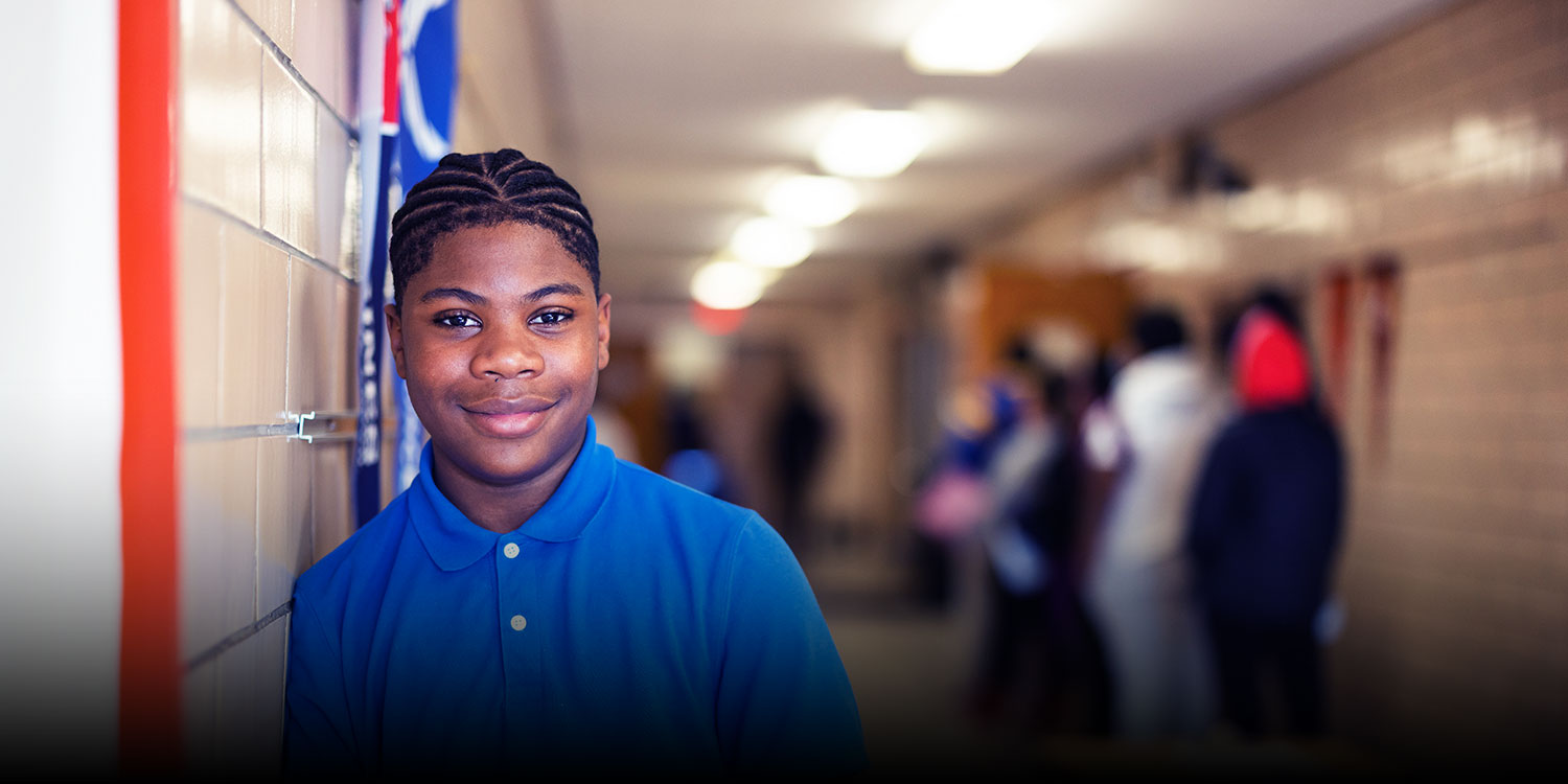 Smiling student in East Academy hallway.